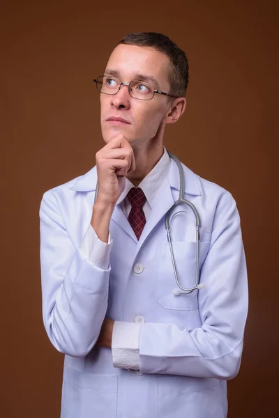 Estúdio tiro de jovem médico contra fundo marrom — Fotografia de Stock