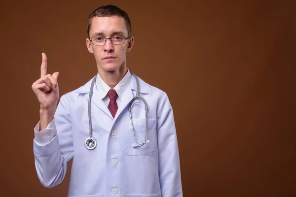 Estúdio tiro de jovem médico contra fundo marrom — Fotografia de Stock