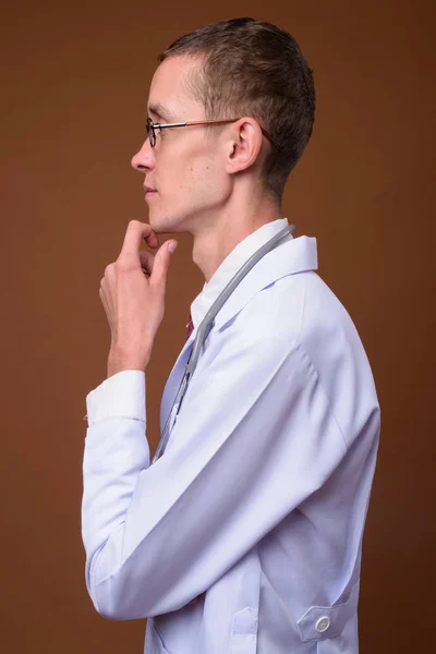 Estúdio tiro de jovem médico contra fundo marrom — Fotografia de Stock