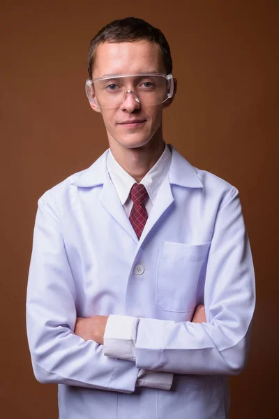 Estúdio Tiro Jovem Médico Vestindo Óculos Proteção Contra Fundo Marrom — Fotografia de Stock