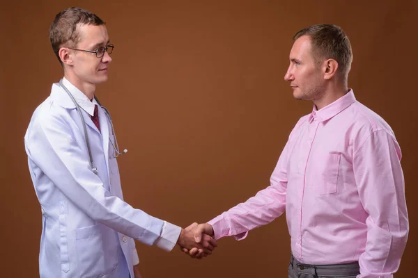 Молодой человек врач и пациент на коричневом фоне — стоковое фото