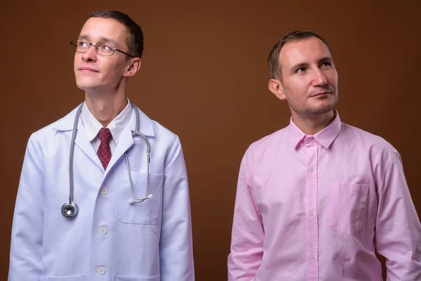 Junger Mann Arzt und Patient vor braunem Hintergrund — Stockfoto