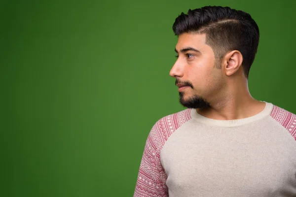 Fiatal szakállas iráni férfi zöld háttérrel — Stock Fotó