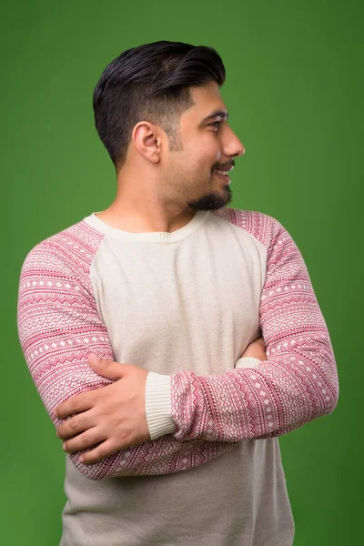 Young bearded Iranian man against green background