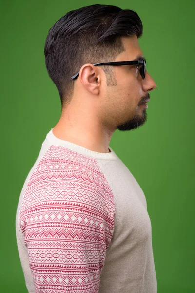 Young bearded Iranian man against green background