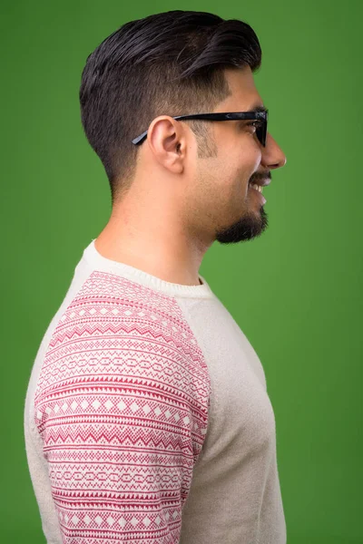 Young bearded Iranian man against green background