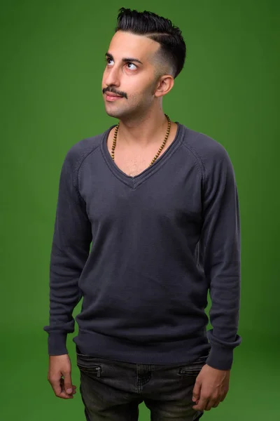 Jovem iraniano bonito com bigode contra backgroun verde — Fotografia de Stock
