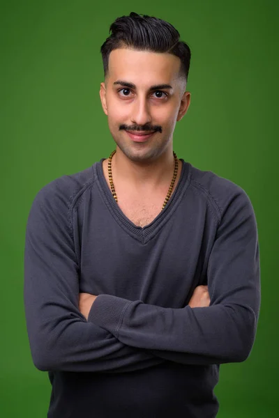 Ung snygg iranska man med mustasch mot gröna bak — Stockfoto