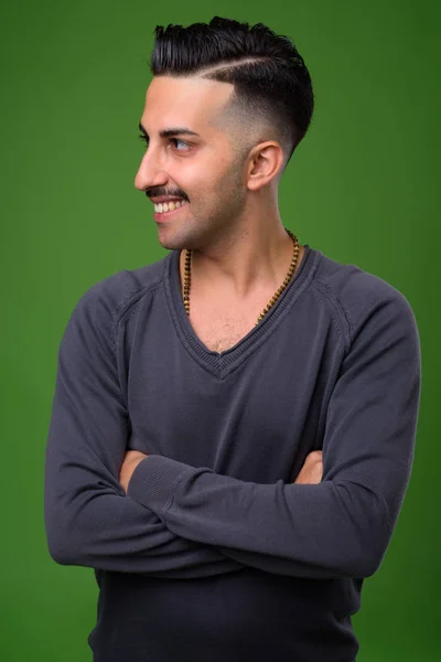 Jovem iraniano bonito com bigode contra backgroun verde — Fotografia de Stock