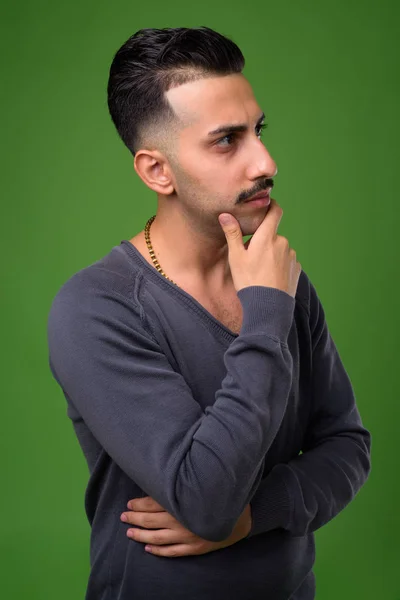 Jovem iraniano bonito com bigode contra backgroun verde — Fotografia de Stock