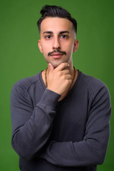Jonge knappe Iraanse man met snor tegen groene pagina — Stockfoto