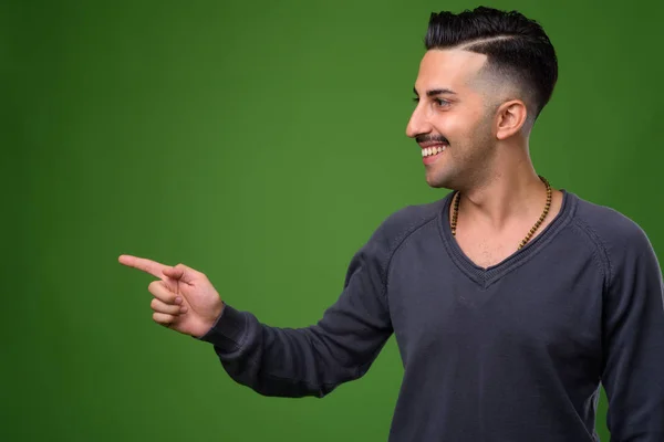 Jovem iraniano bonito com bigode contra backgroun verde — Fotografia de Stock