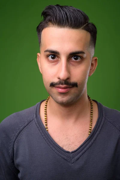 Jovem iraniano bonito com bigode contra backgroun verde — Fotografia de Stock