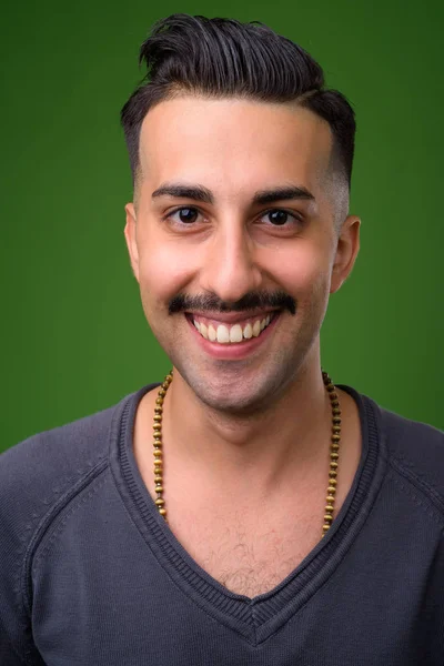 Jovem iraniano bonito com bigode contra backgroun verde — Fotografia de Stock