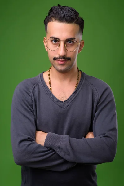 Młody przystojny irański mężczyzna z wąsem przeciwko zielony deseń — Zdjęcie stockowe