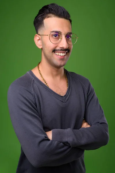 Jovem iraniano bonito com bigode contra backgroun verde — Fotografia de Stock