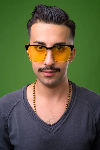 Jovem iraniano bonito com bigode contra backgroun verde — Fotografia de Stock