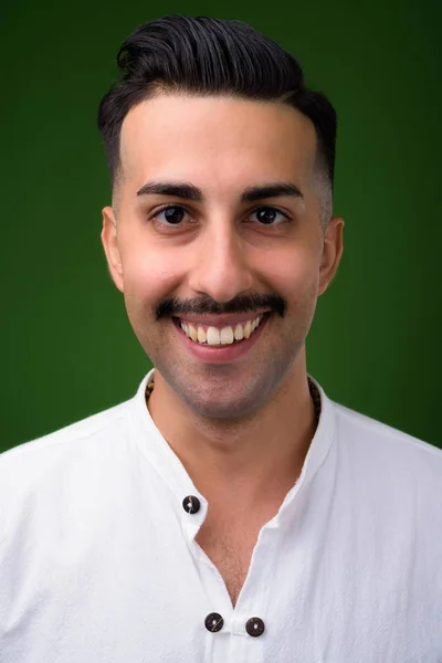 Ung snygg iranska man med mustasch mot gröna bak — Stockfoto