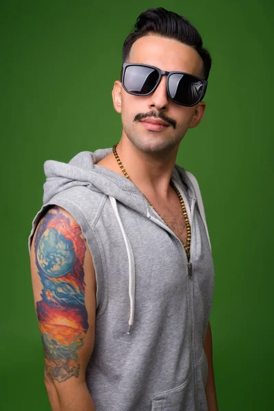 Jovem iraniano bonito com bigode contra backgroun verde — Fotografia de Stock