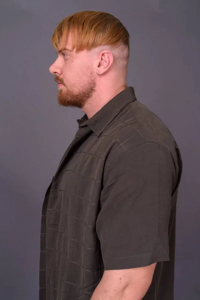 Vousatý muž s blond vlasy proti šedému pozadí — Stock fotografie
