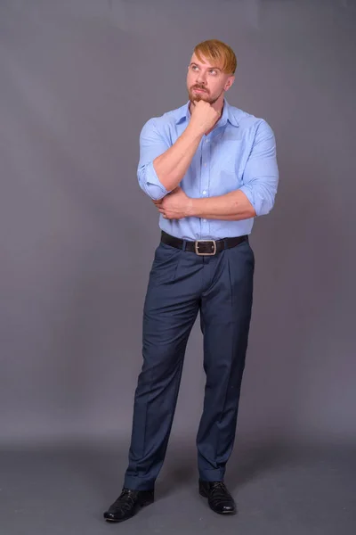 Бородатий бізнесмен з світлим волоссям на сірому фоні — стокове фото