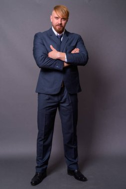 Sakallı iş adamı, sarı saçlı, gri arka planda.