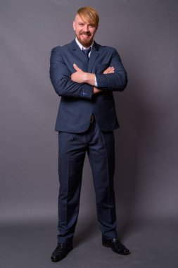 Sakallı iş adamı, sarı saçlı, gri arka planda.