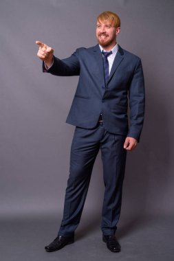 Sakallı iş adamı, sarı saçlı, gri arka planda.