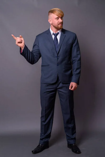 Uomo d'affari barbuto con i capelli biondi sullo sfondo grigio — Foto Stock
