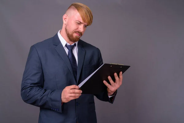 Bearded businessman with blond hair against gray background — Stock Photo, Image