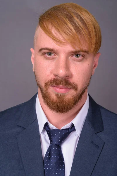 Homem de negócios barbudo com cabelo loiro contra fundo cinza — Fotografia de Stock