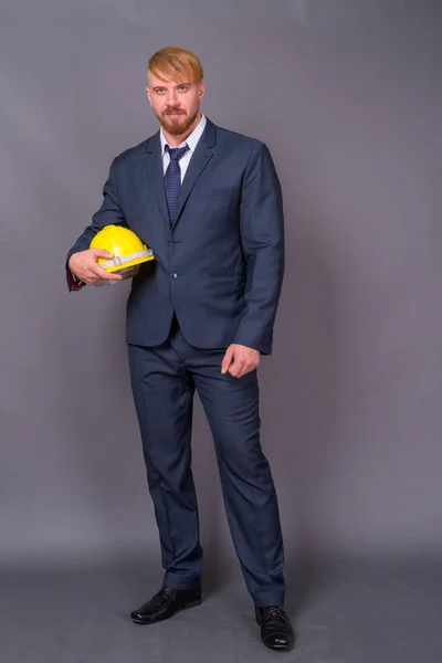 Barbuto uomo d'affari con hardhat contro sfondo grigio — Foto Stock