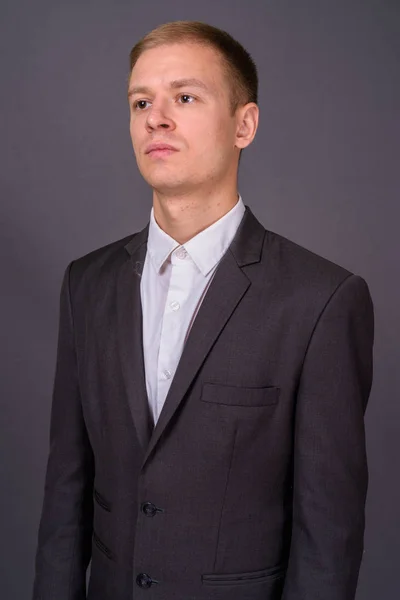 Portret młodego przystojnego biznesmena na szarym tle — Zdjęcie stockowe