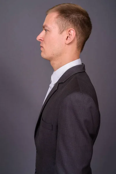 Retrato de jovem empresário bonito contra fundo cinza — Fotografia de Stock