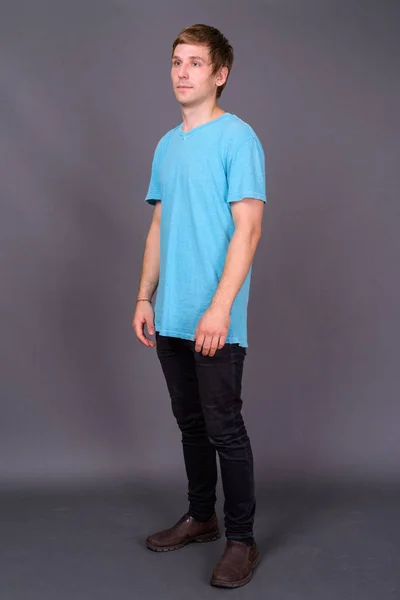 Portrait of young handsome man against gray background — Stock Photo, Image