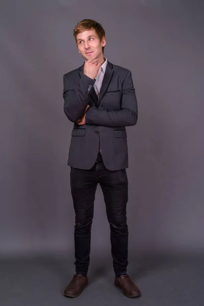 Porträt eines jungen, gut aussehenden Geschäftsmannes vor grauem Hintergrund — Stockfoto