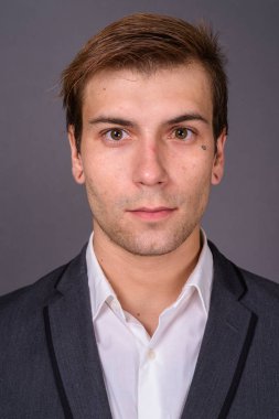 Genç yakışıklı işadamı gri arka plan portait