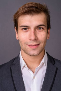 Genç yakışıklı işadamı gri arka plan portait