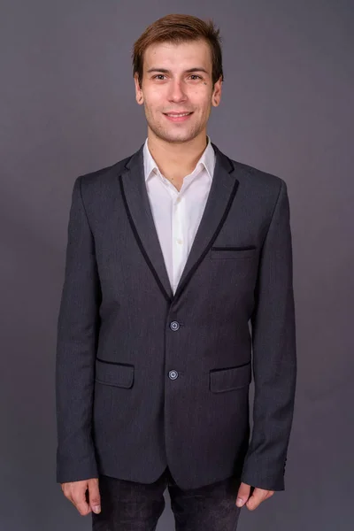 Портрет молодого привлекательного бизнесмена на сером фоне — стоковое фото