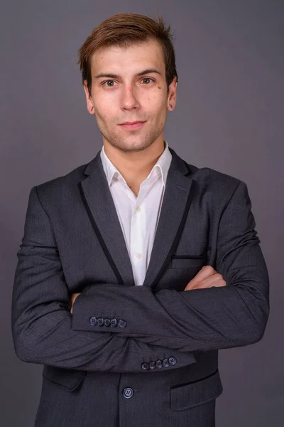 Porträt eines jungen gutaussehenden Geschäftsmannes vor grauem Hintergrund — Stockfoto