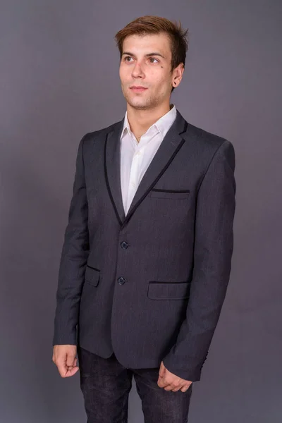 Fiatal, jóképű üzletember sötétszürke háttérrel portréja — Stock Fotó