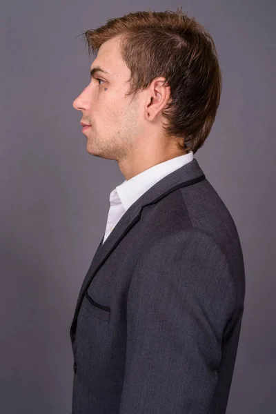 Portait of young handsome businessman against gray background — Stock Photo, Image