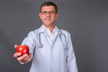 Gri arka planda kısa saçlı yakışıklı bir doktor.