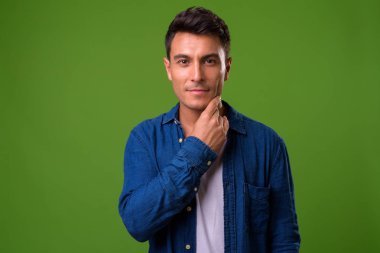 Genç yakışıklı İspanyol adam yeşil bir arka plana dayanır