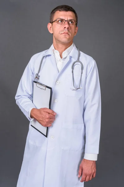 Pohledný muž lékař s krátkými vlasy proti šedému pozadí — Stock fotografie