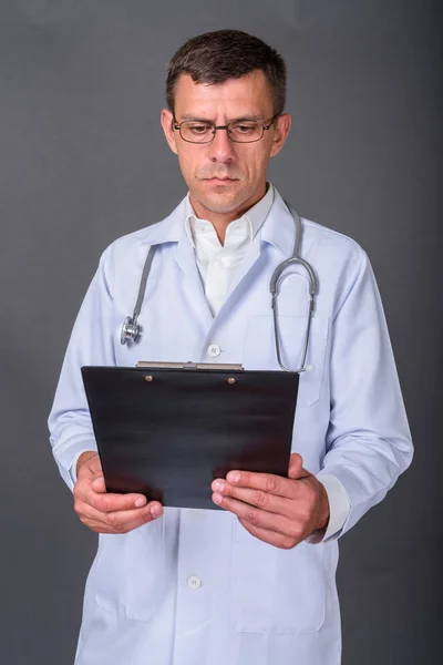 Hombre guapo doctor con pelo corto sobre fondo gris — Foto de Stock