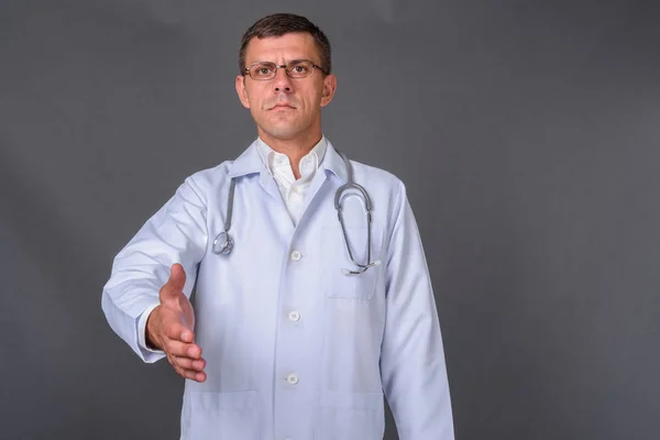 회색 배경에 대해 짧은 머리를 하고 있는 다루기 쉬운 남자 의사 — 스톡 사진