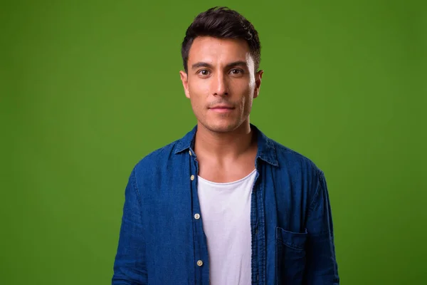 Jonge knappe man van de Hispanic tegen groene achtergrond — Stockfoto