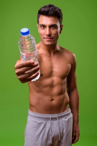 Jovem bonito hispânico homem sem camisa contra fundo verde — Fotografia de Stock