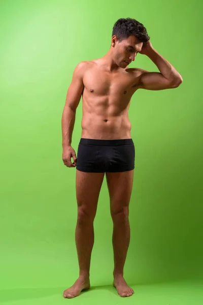 Jovem bonito hispânico homem sem camisa contra fundo verde — Fotografia de Stock